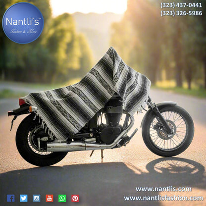 Motorcycle with a striped cover on a road with trees in the background, featuring Nantli's branding.