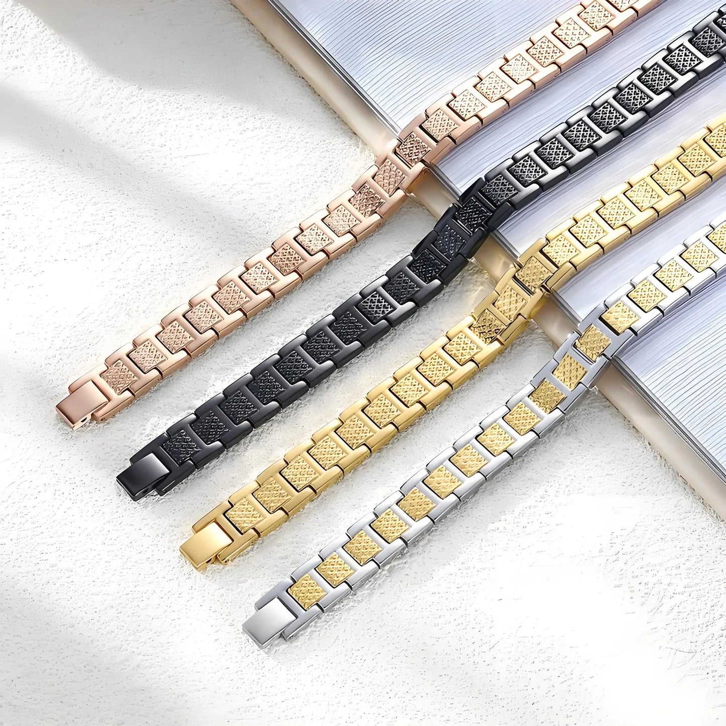 Four metallic bracelets in rose gold, black, gold, and silver on a light background. Nantlis